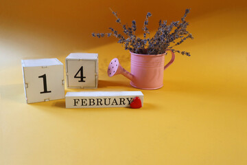 Calendar for February 14: lavender bouquet in a pink watering can, red heart, numbers one and four, name of the month in English, yellow background, side view
