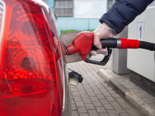 a man fills a car with gasoline in a disposable glove. safety from germs. stop the coronavirus
