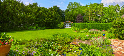 Well-kept garden with a colorful flower bed, garden shed and pond.