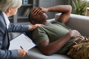 African soldier lying on sofa and talking to therapist during psychological therapy