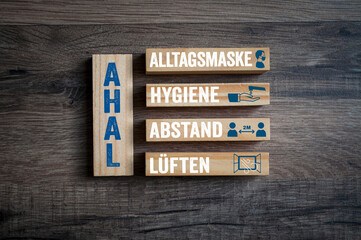 Pieces of wood with covid-19 corona virus and the german acronym for AHAL - Abstand, Hygiene,...