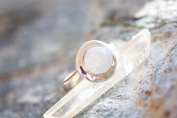 Sterling silver ring with moon stone on natural neutral background with crystal quartz
