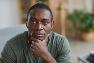 Portrait of African man looking at camera sitting in the room