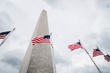 American flags waving in the wind around the Washington Monument in Washington, D.C.