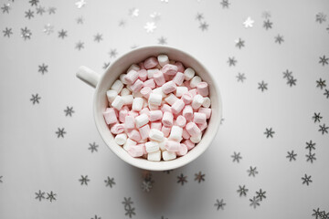 cup with marshmallows on a white background with silver snowflakes