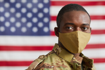 Portrait of African american man in protective mask looking at camera standing against the American flag