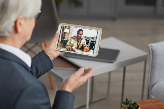 Rear View Of Woman Holding Digital Tablet And Talking To African Soldier Online