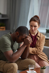 Obraz premium African man worried about his problems with woman sitting near by and supporting him