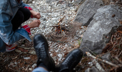 girl in red shirt and black jeans makes fire in forest. Human and nature. Traveler girl alone on mountain. Feeling freedom in camp