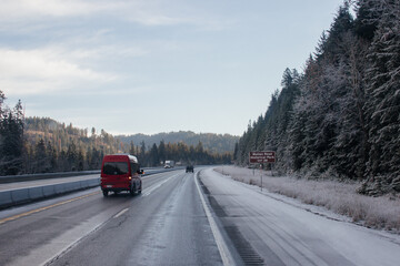 The road in winter, along which cars travel, among snow-covered trees and frost-covered roadsides. Idaho, USA, 11-23-2019