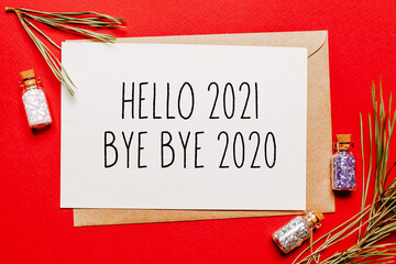 Obraz na płótnie Canvas hello 2021 bye bye 2020 christmas note with gift, fir branch and toy on red isolated background. New Year concept