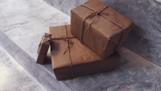 Packaged boxes for postal delivery service, parcels wrapped in brown paper and tied with rough twine in warehouse, concrete background with copyspace for design