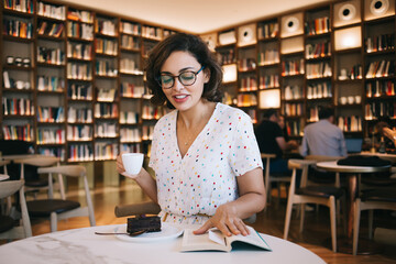 Woman drinking coffee and reading in cafe