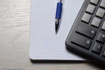 a ballpoint pen and a micro calculator lie on a squared notebook. close-up.