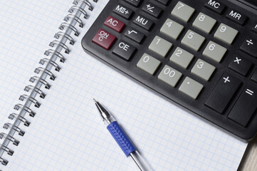 a ballpoint pen and a micro calculator lie on a squared notebook. close-up.