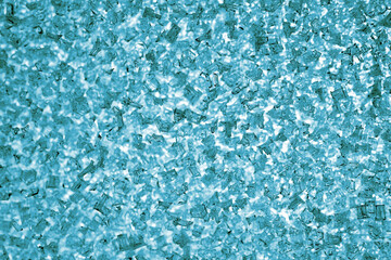 Light blue green tinted winter background or wallpaper. Ice crystals on the window pane close-up. The backdrop looks like a pile of broken glass. Top view from above. Macro