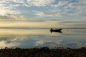 Reflections of the dawn sky on an ocean bay with a boat