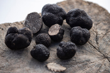 Some black truffles over a wooden surface and an oak leaf.