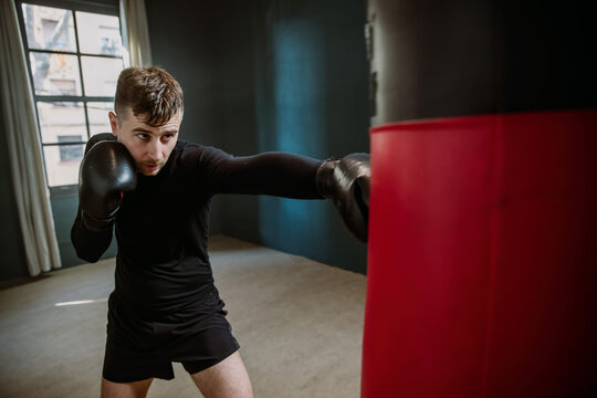 A man boxer beats a punching bag. Boxer practicing punches in the ring. The athlete strikes with a punching bag. 4k video - Powered by Adobe