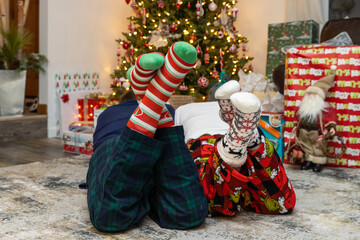 Two people laying by the Christmas tree in pajamas and colorful socks