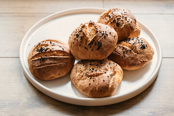 Homemade breads on a white plate. Small organic breads. Sesame and black seed breads.