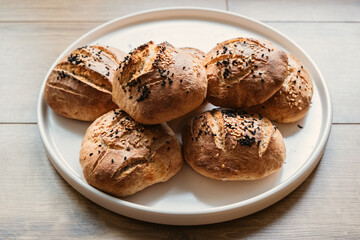 Homemade breads on a white plate. Small organic breads. Sesame and black seed breads.