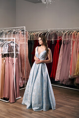 Young beautiful brunette girl wearing a full-length draped sky blue satin slit prom ball gown...