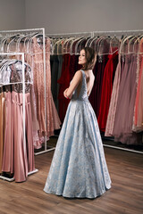 Young beautiful brunette girl wearing a full-length draped sky blue satin slit prom ball gown...