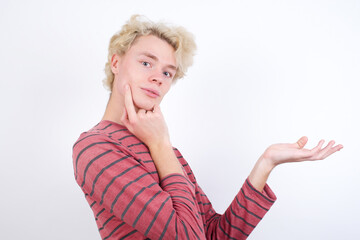 Funny Young handsome Caucasian blond man standing against white background hold open palm new product great proposition