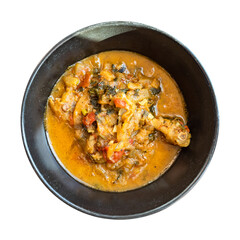 top view of cooked Chakhokhbili (traditional georgian dish from stewed chicken meat, tomato, eggplant and fresh herbs) in black bowl cutout on white background
