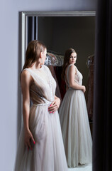 Young beautiful brunette girl wearing a full-length silver white chiffon prom ball gown decorated...