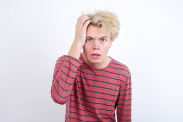 Embarrassed Young handsome Caucasian blond man standing against white background with shocked expression, expresses great amazement, Puzzled model poses indoor