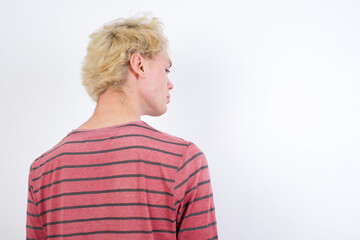 The back side view of a Young handsome Caucasian blond man standing against white background. Studio Shoot.