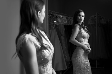 Young beautiful brunette girl wearing a full-length fitting chiffon prom ball slit gown decorated...