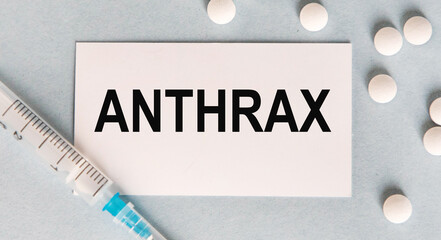 On the card text ANTHRAX, next to a syringe and white tablets.