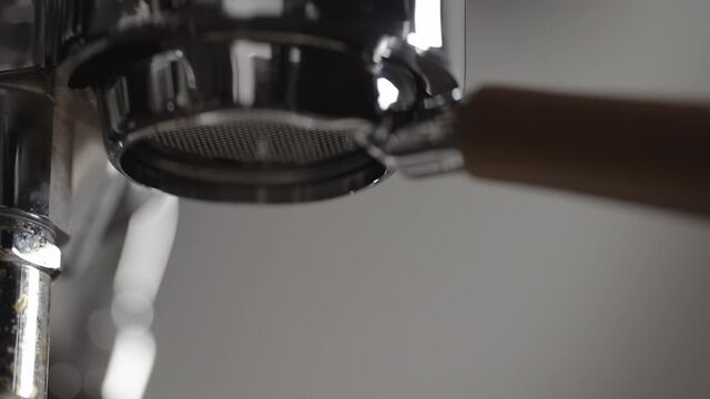 Slow motion low angle shot of espresso extraction from naked portafilter into white cup