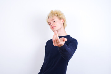 Young handsome Caucasian blond man standing against white background inviting to come with hand. Happy that you came