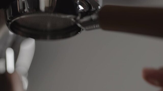 Slow motion low angle shot man put naked portafiler in coffee machine