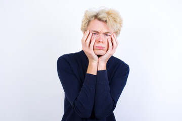 Young handsome Caucasian blond man standing against white background Tired hands covering face, depression and sadness, upset and irritated for problem