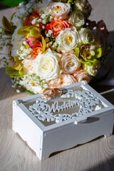 Wedding rings, gift box and flowers for the bride.