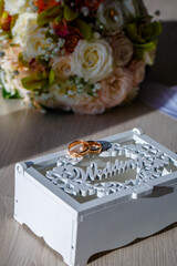 Wedding rings, gift box and flowers for the bride.