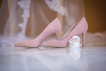 Women's peach shoes. Nearby on the veil are the wedding rings of the bride and groom.