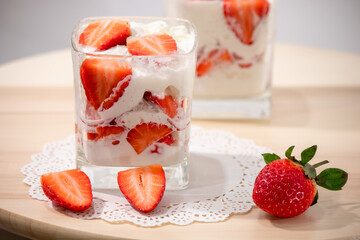 Strawberries with whipped cream in a glass on a wooden table
