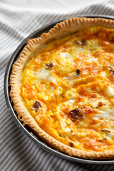 Homemade Bacon Quiche with Eggs and Cheddar Cheese on cloth, low angle view.