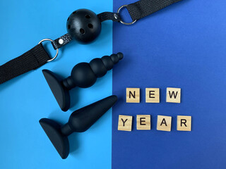 Sex toys and Inscription NEW YEAR. Gag and butt plugs. Blue background. Useful for adult, sex shop