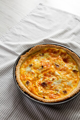 Homemade Bacon Quiche with Eggs and Cheddar Cheese on cloth, side view. Copy space.