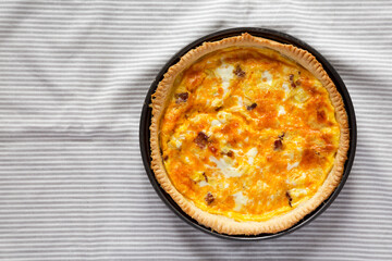 Homemade Bacon Quiche with Eggs and Cheddar Cheese on cloth, overhead view. Flat lay, from above, top view. Copy space.