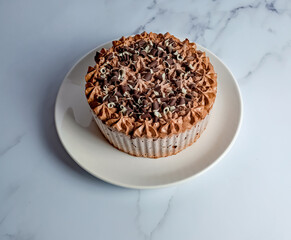 Norwich, Norfolk, UK – December 25 2020. An illustrative editorial photograph of a close up of a frozen double chocolate gateau on a white plate on a marbled white kitchen worktop