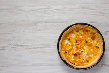 Homemade Bacon Quiche with Eggs and Cheddar Cheese on a white wooden background, overhead view. Flat lay, from above, top view. Copy space.