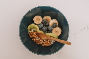 muesli bowl with sliced banana, blueberry, kiwi and strawberry on wooden table, closeup view. Healthy eating, healthy breakfast dieting concept